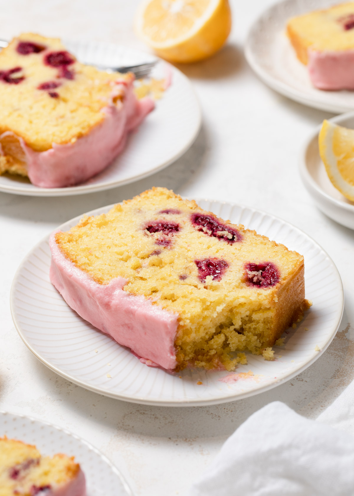 A close-up of a bite taken out of a raspberry lemon loaf cake with pink icing