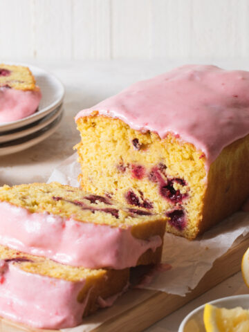 A sliced raspberry lemon loaf cake with pink icing on top