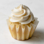 A cupcake with piped vanilla whipped buttercream frosting on top