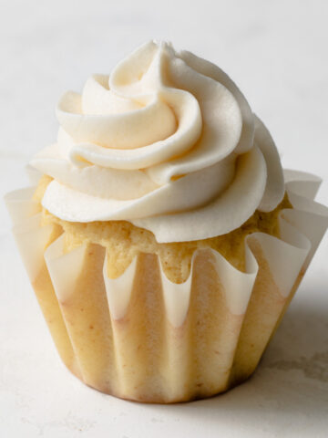 A cupcake with piped vanilla whipped buttercream frosting on top