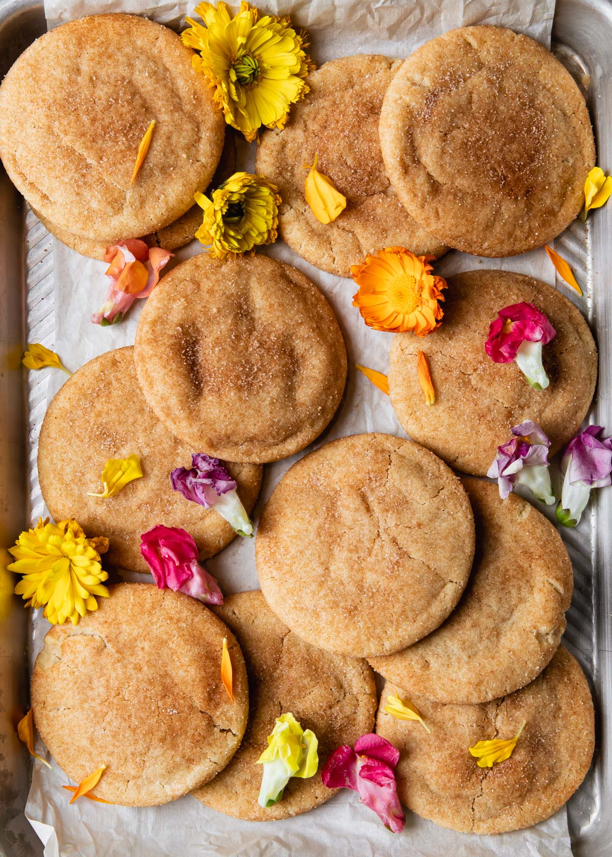 A baking sheet full of brown butter snickerdoodles and edible flowers