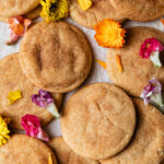 A baking sheet full of brown butter snickerdoodles and edible flowers