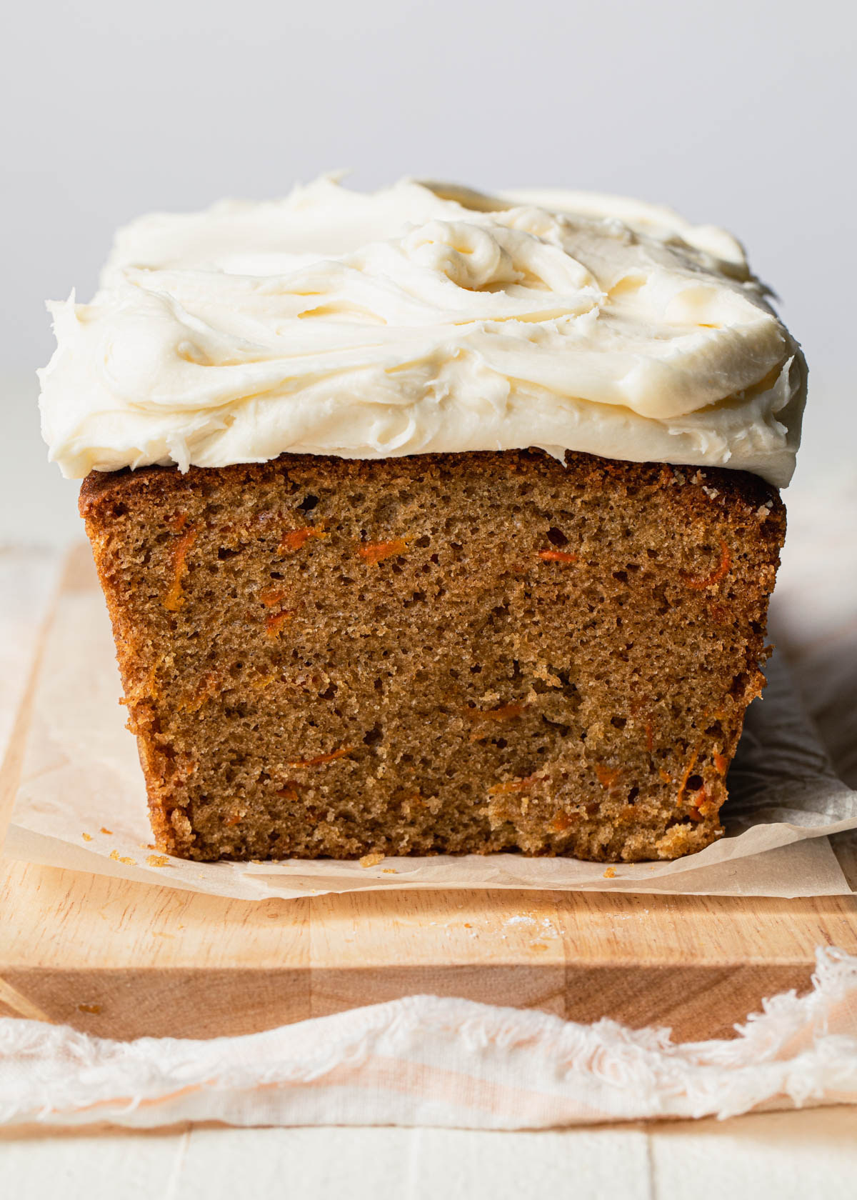 A close-up cross section of a carrot loaf cake with cream cheese frosting