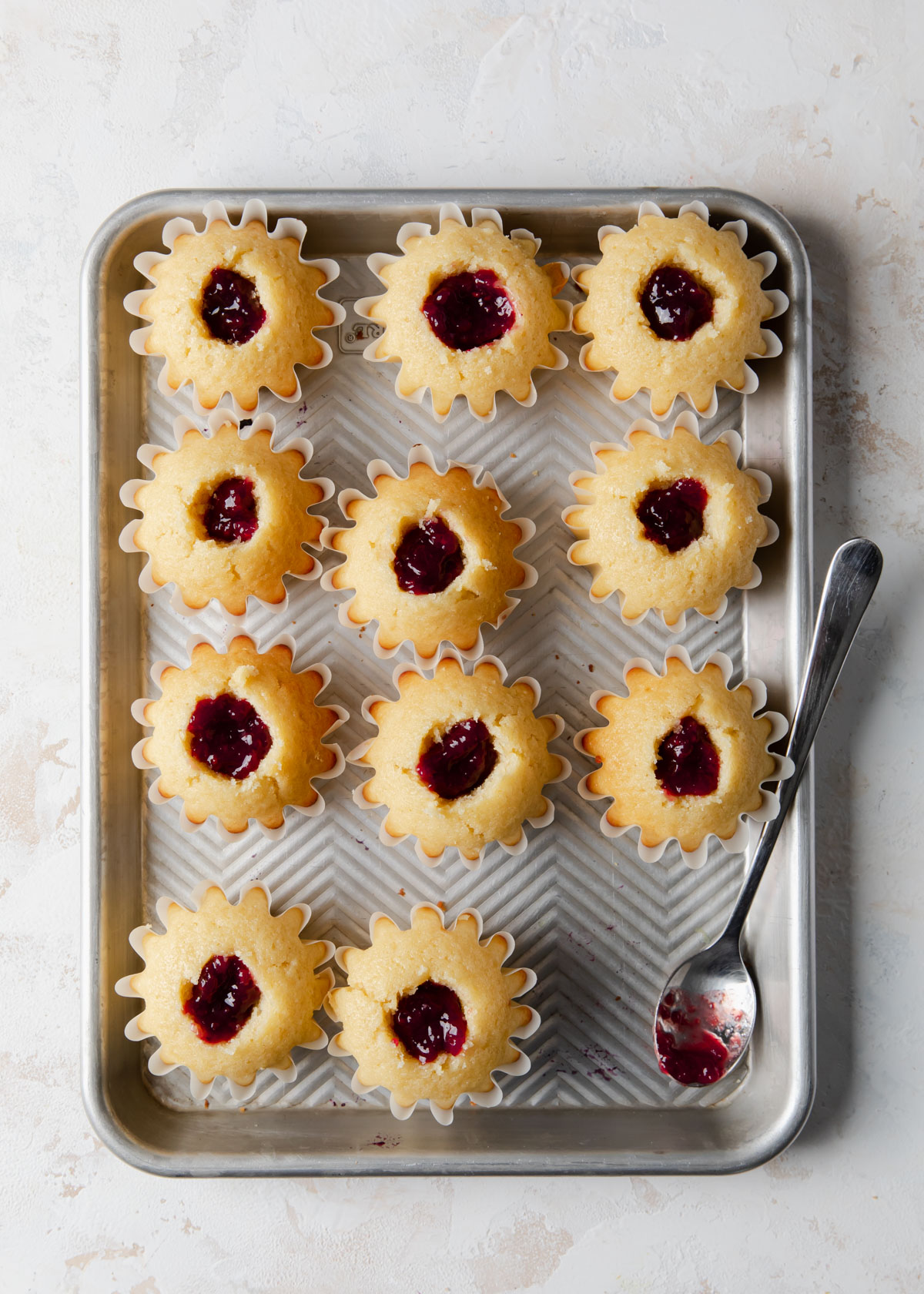 Cupcakes filled with raspberry jam on a baking sheet