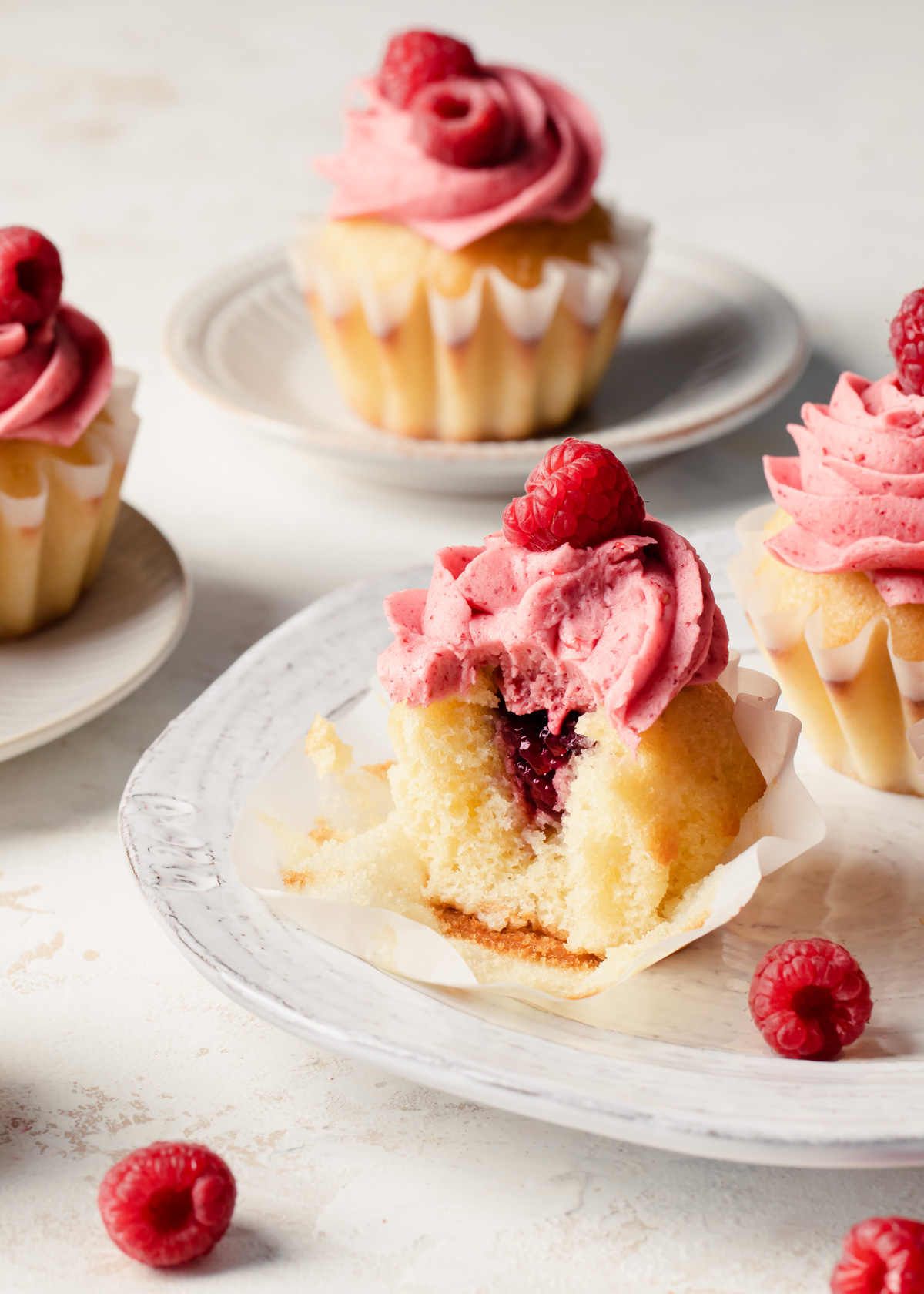 A bite taken out of a raspberry cupcake to expose the jam filling