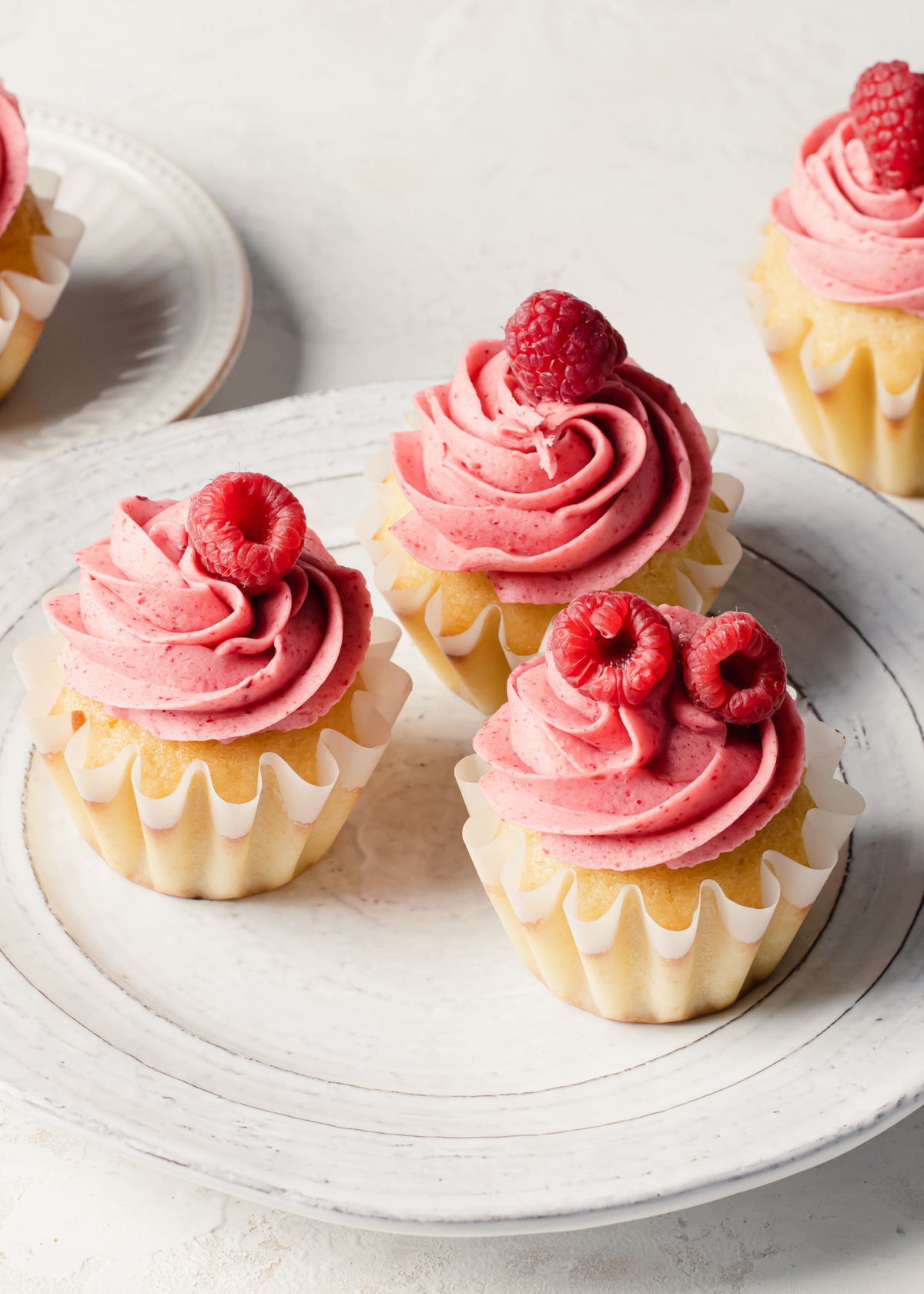 A trio of raspberry cupcakes with fresh berries on top