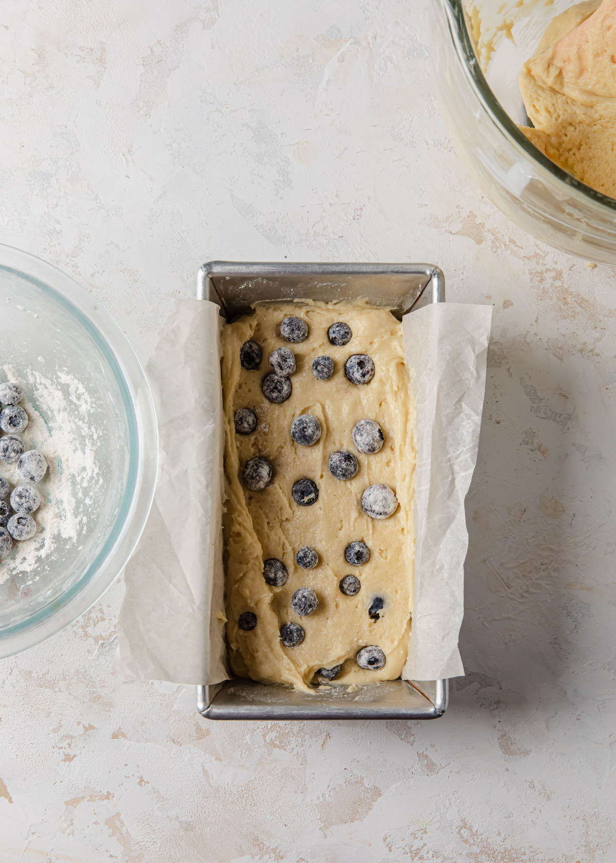 adding blueberry cake batter into a loaf pan