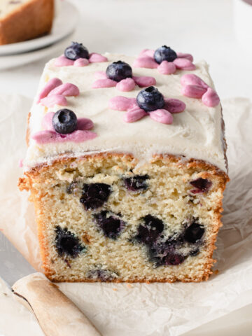 A tabletop scene with a cut open blueberry pound cake