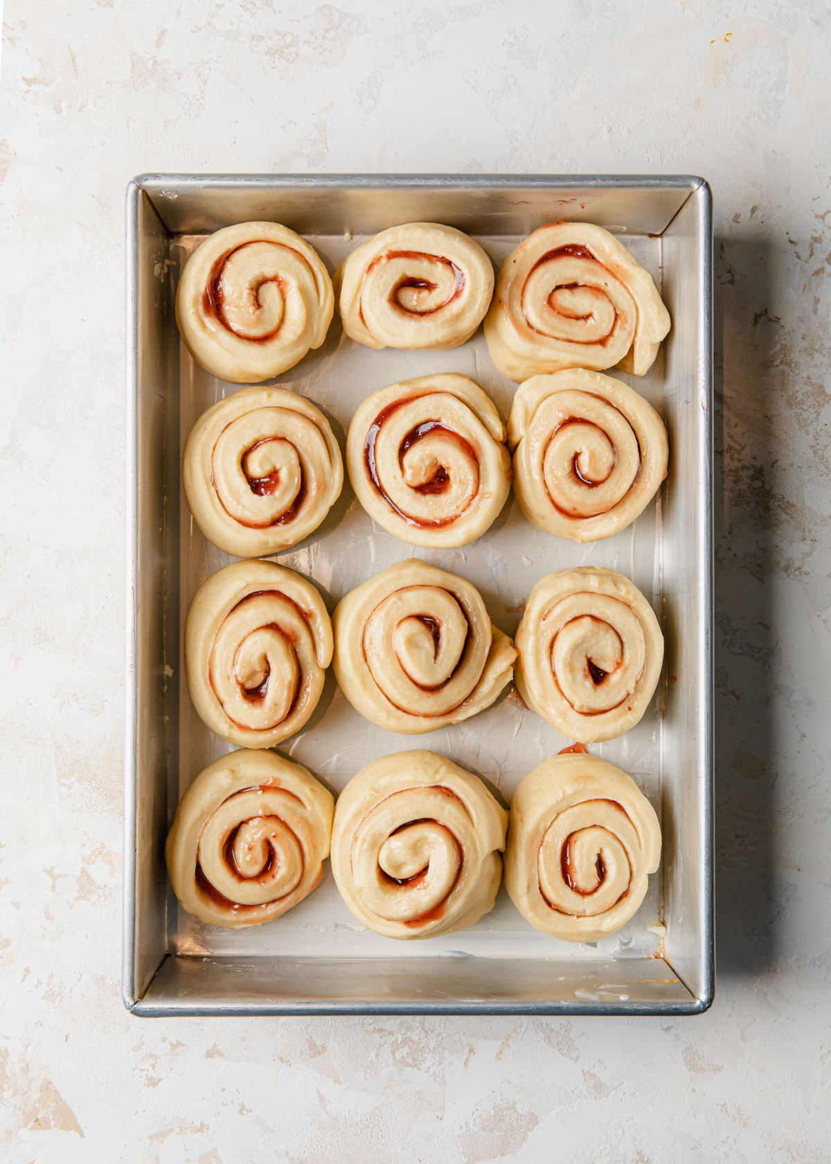 Strawberry jam rolls proofing in a pan before baking