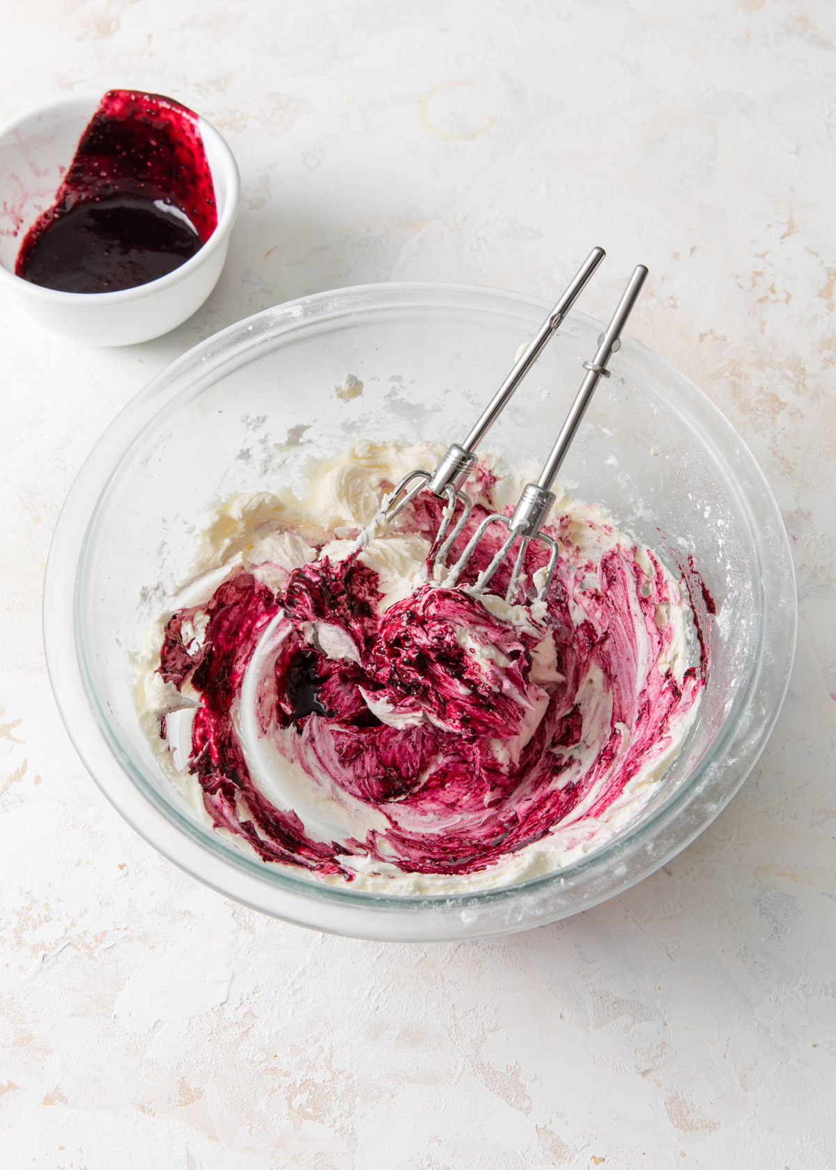 Mixing in the blueberry sauce to whipped buttercream frosting