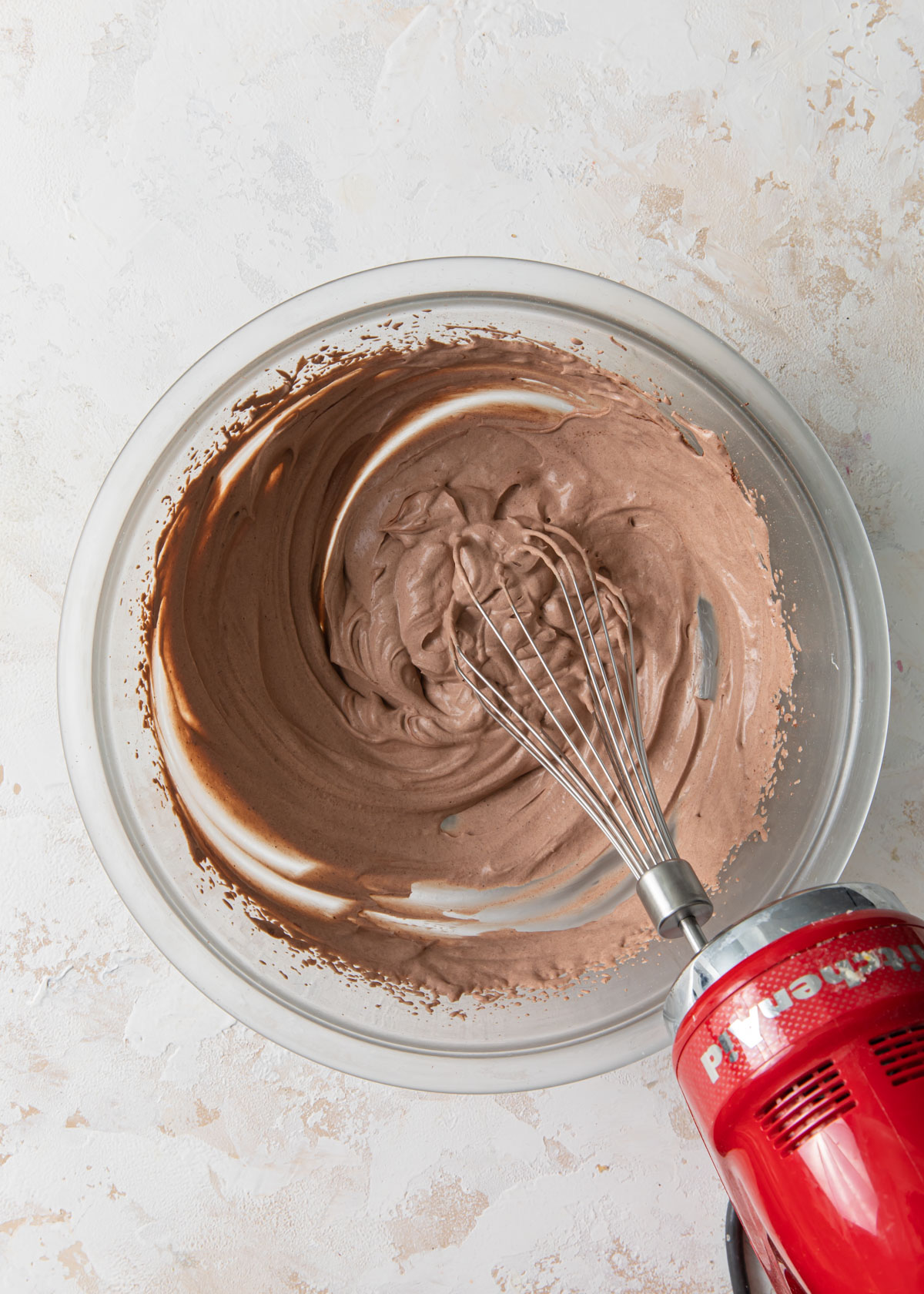 Chocolate whipped cream being whisked in a bowl and starting to thicken