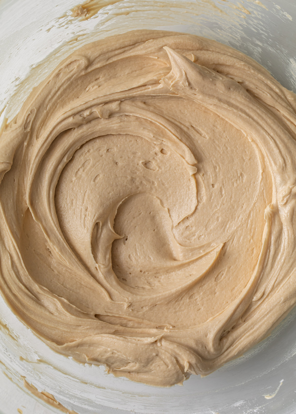 a close up of smooth coffee buttercream in a glass bowl