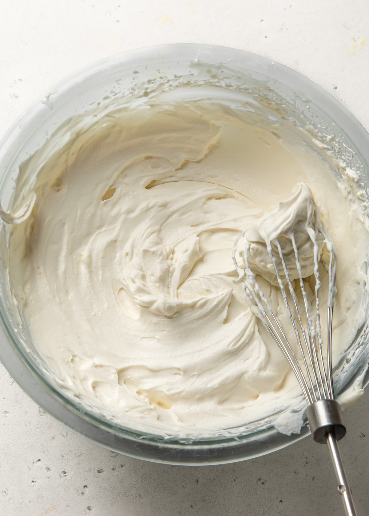 A bowl of stabilized whipped cream with a whisk inside