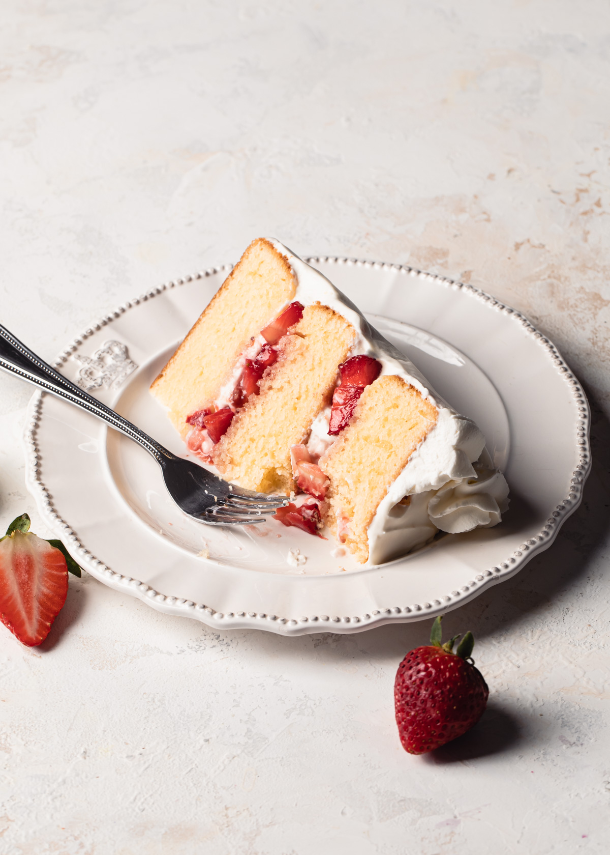 A slice of strawberry layer cake frosting with whipped cream