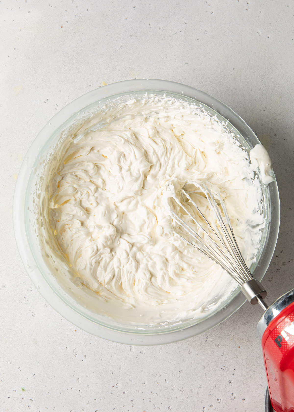Whipped cream that has reached stiff peaks in a glass bowl