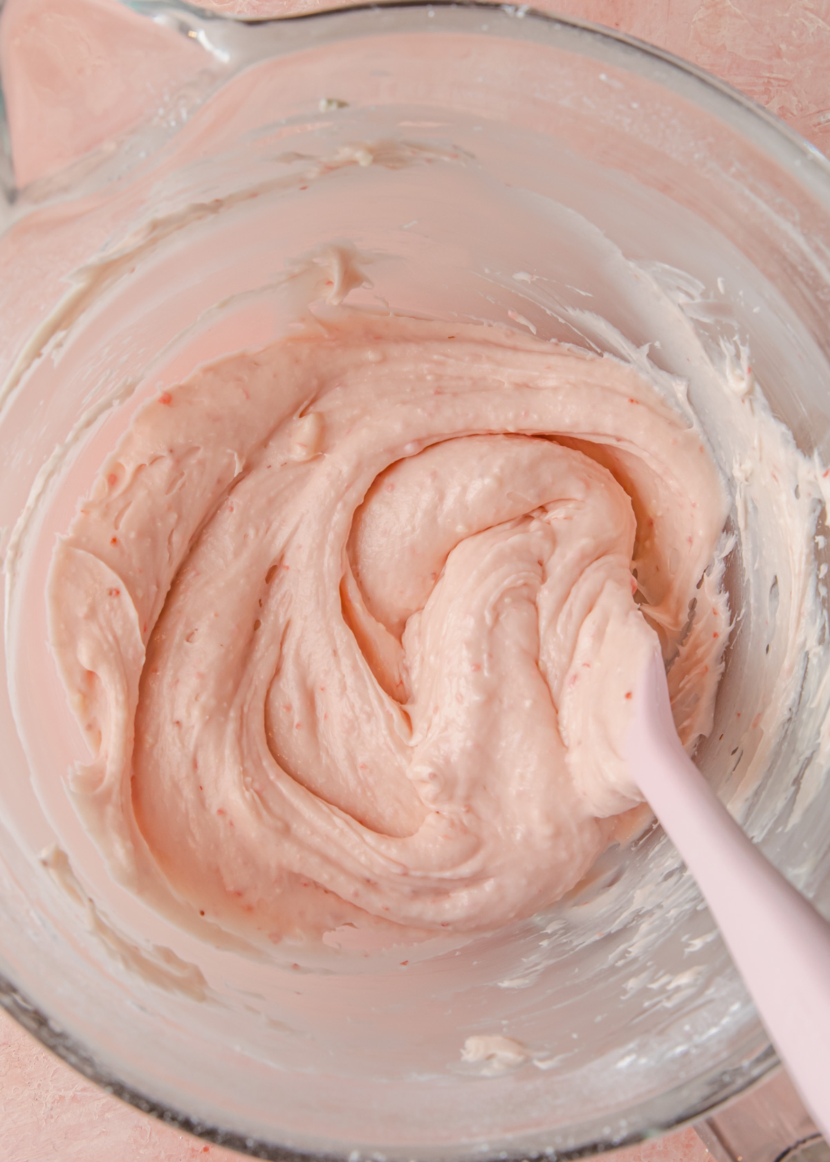 A mixing bowl full of strawberry cream cheese frosting