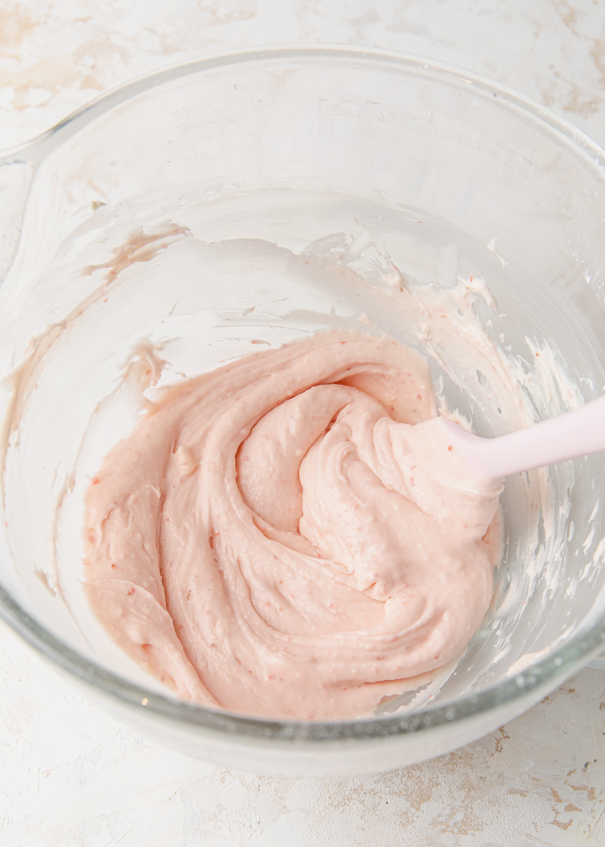 A mixing bowl full of strawberry cream cheese frosting