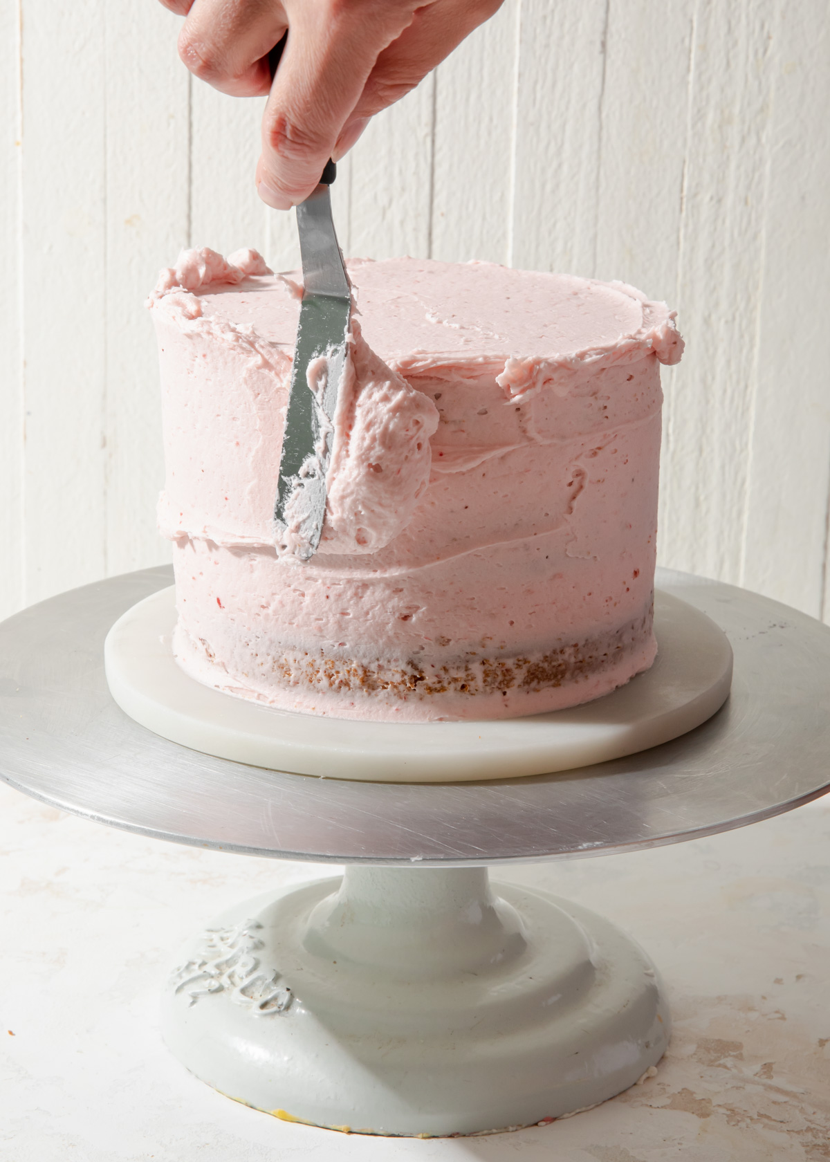 Icing a cake with strawberry buttercream