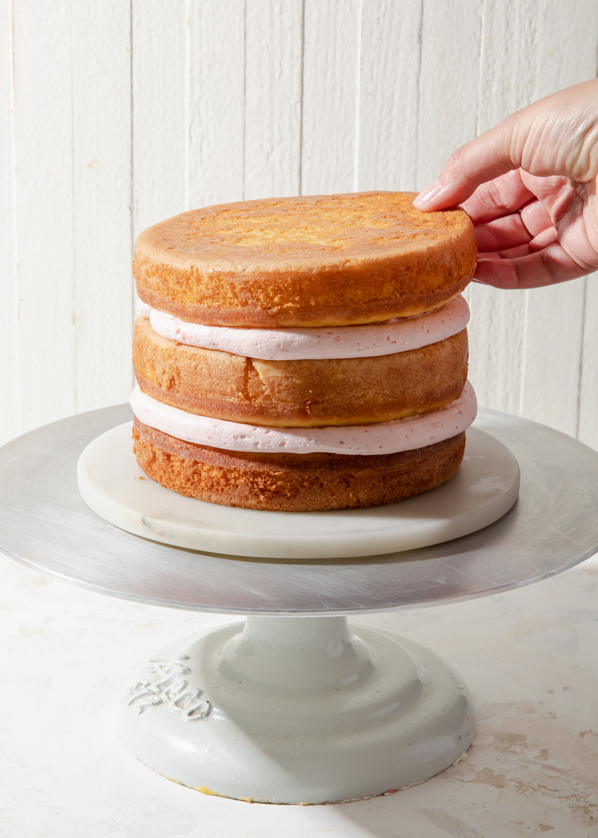 Stacking a three layer vanilla cake with strawberry filling