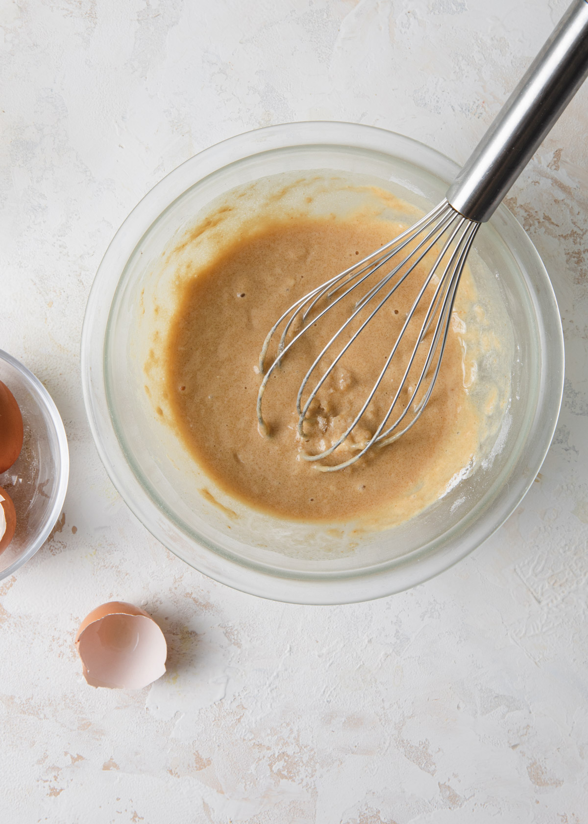 Adding eggs and milk to batter with a whisk