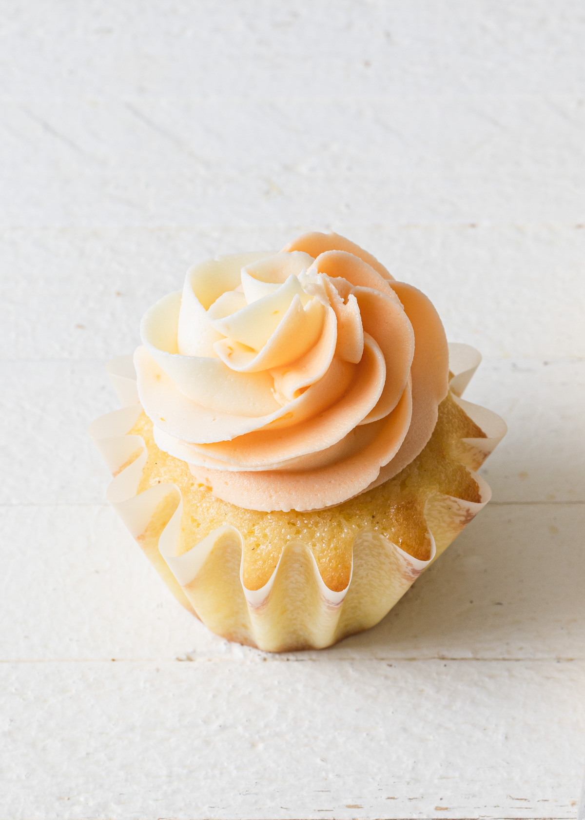 Swirls of piped orange buttercream on top a a cupcake