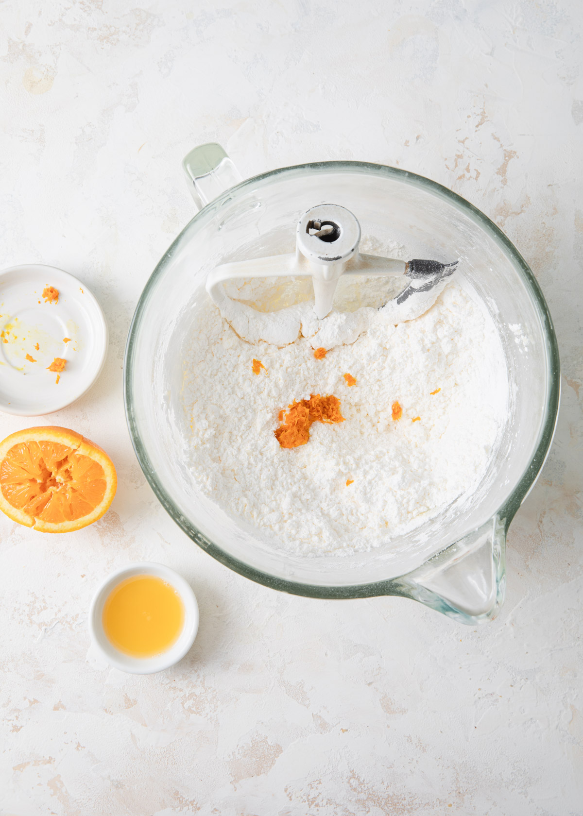 Powdered sugar and orange zest being added to buttercream