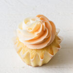 Swirls of piped orange buttercream on top a a cupcake