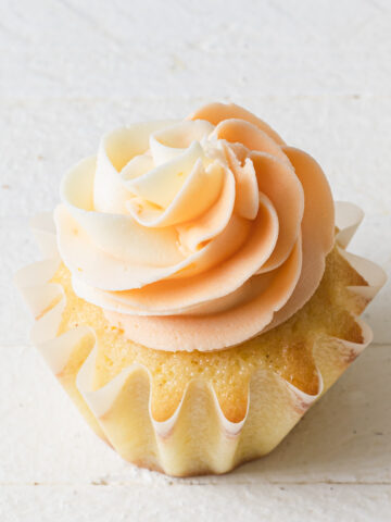 Swirls of piped orange buttercream on top a a cupcake