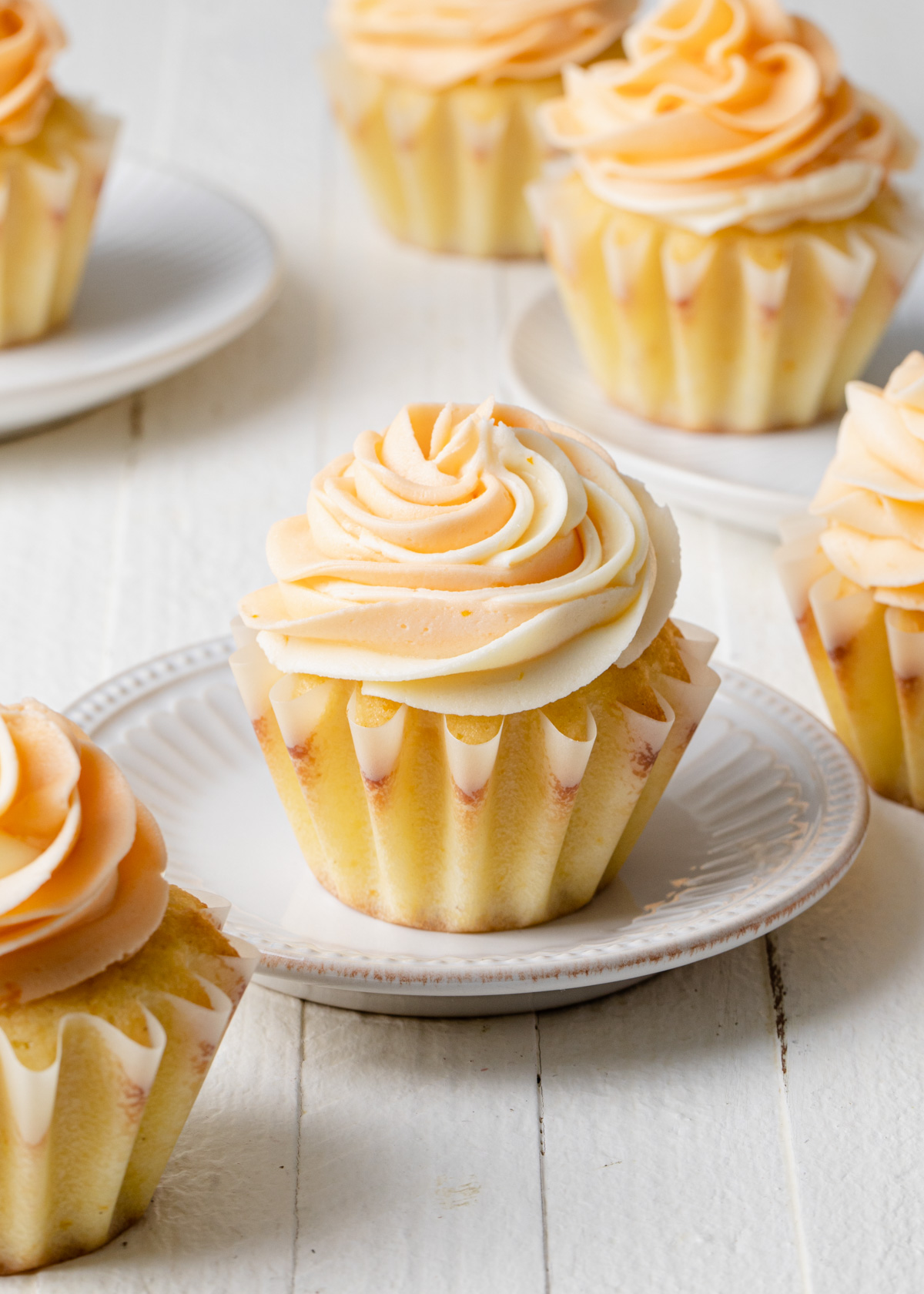 A close up of a cupcake with swirls of orange buttercream on top