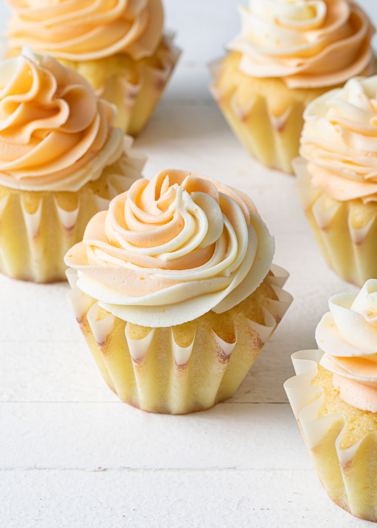 A white background with a cupcake and swirls of orange buttercream piped on top
