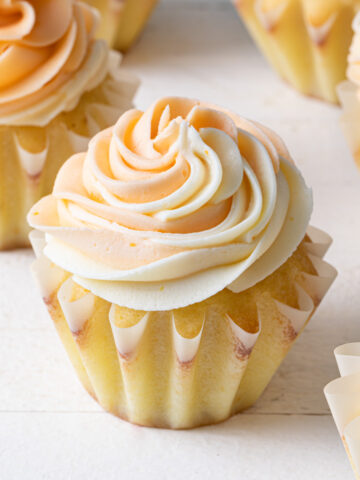 A white background with a cupcake and swirls of orange buttercream piped on top