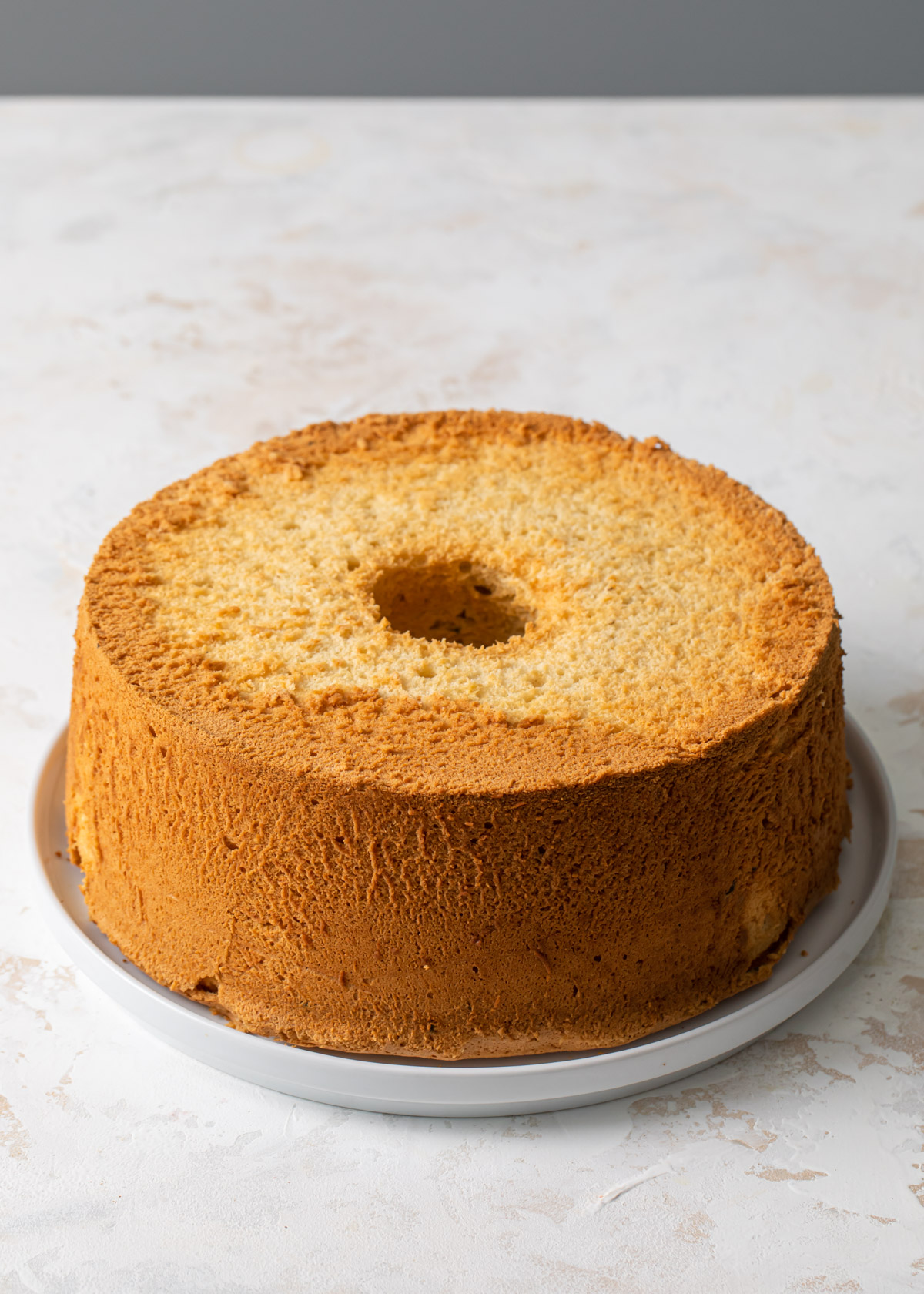 A plain baked vanilla chiffon cake on a white plate