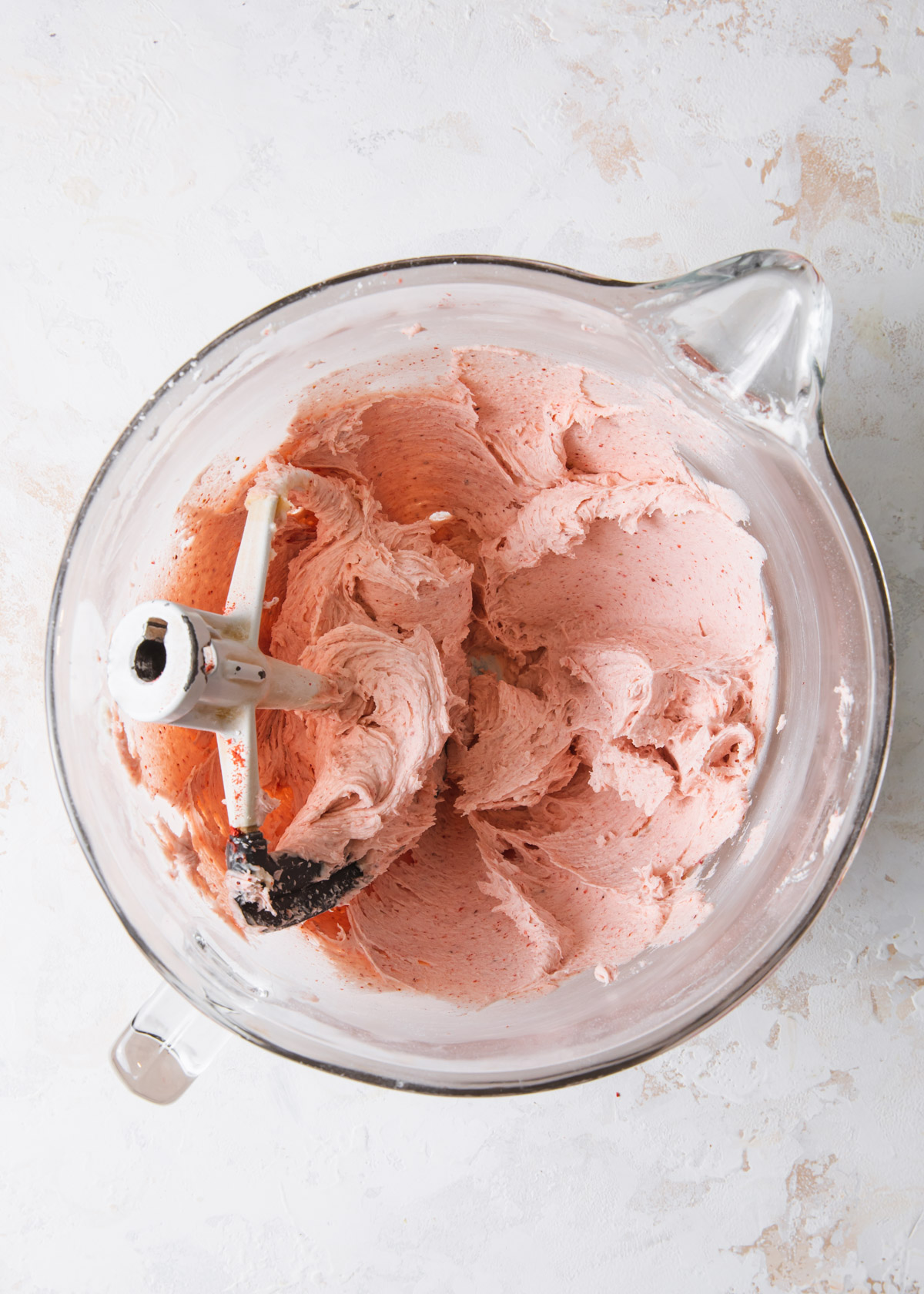 Whipped strawberry frosting in a glass mixing bowl