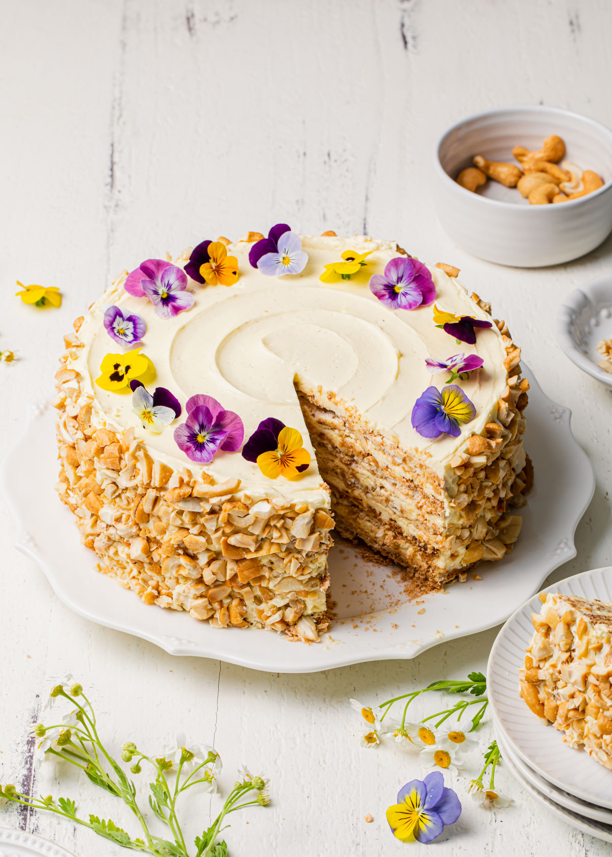 A layered cashew and meringue Sans Rival Cake that's been sliced and served on a white platter