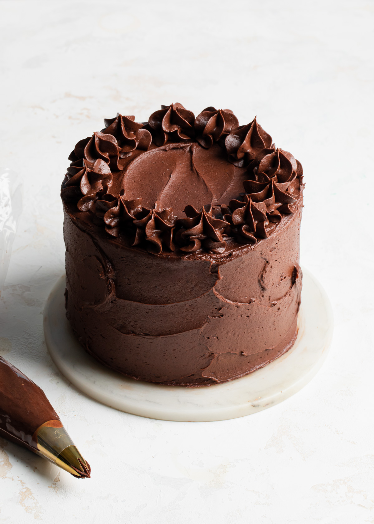 A fully frosted chocolate orange cake with piped fudge frosting on top