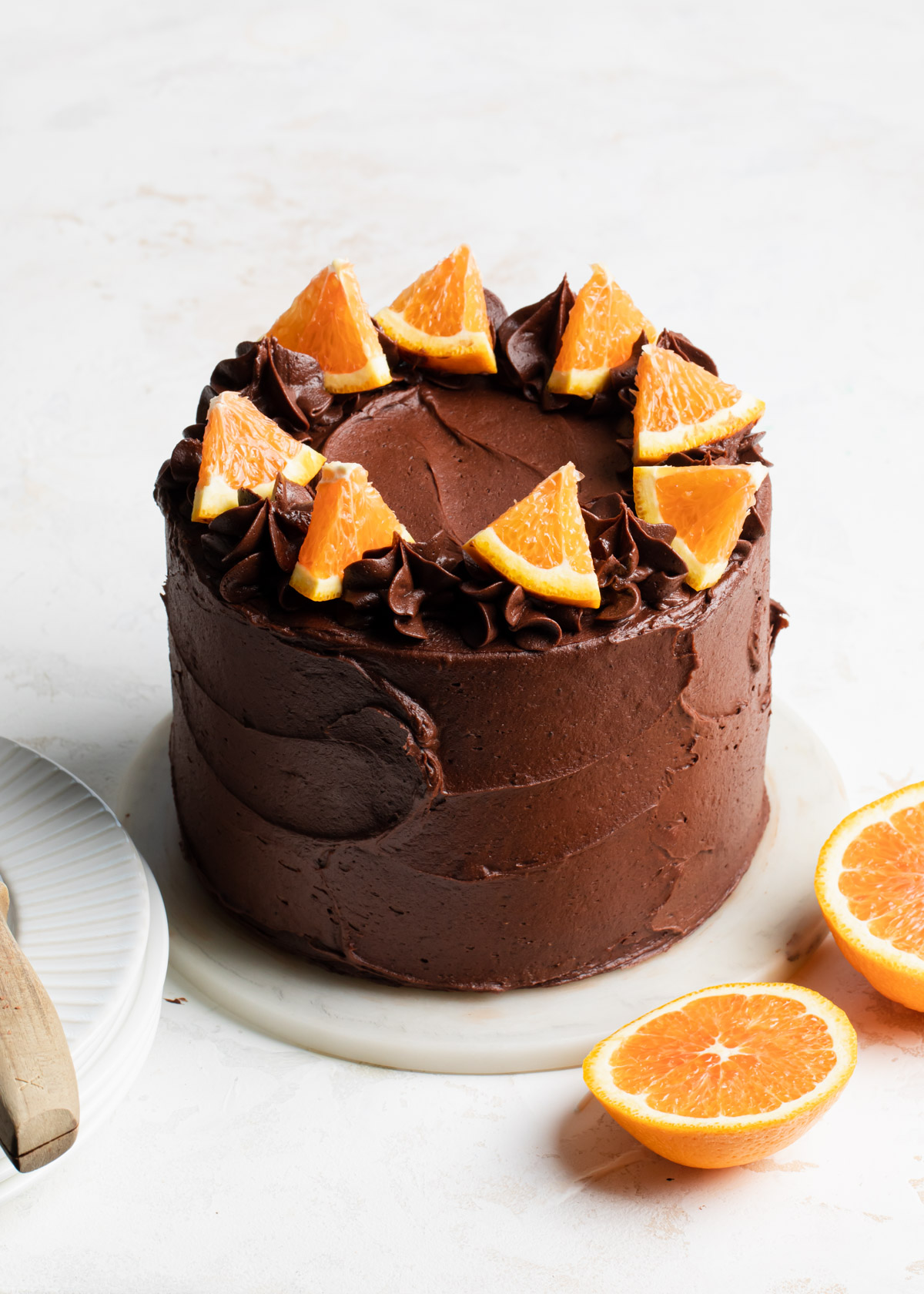 A chocolate layer cake and fudge frosting with slices of fresh orange on top.
