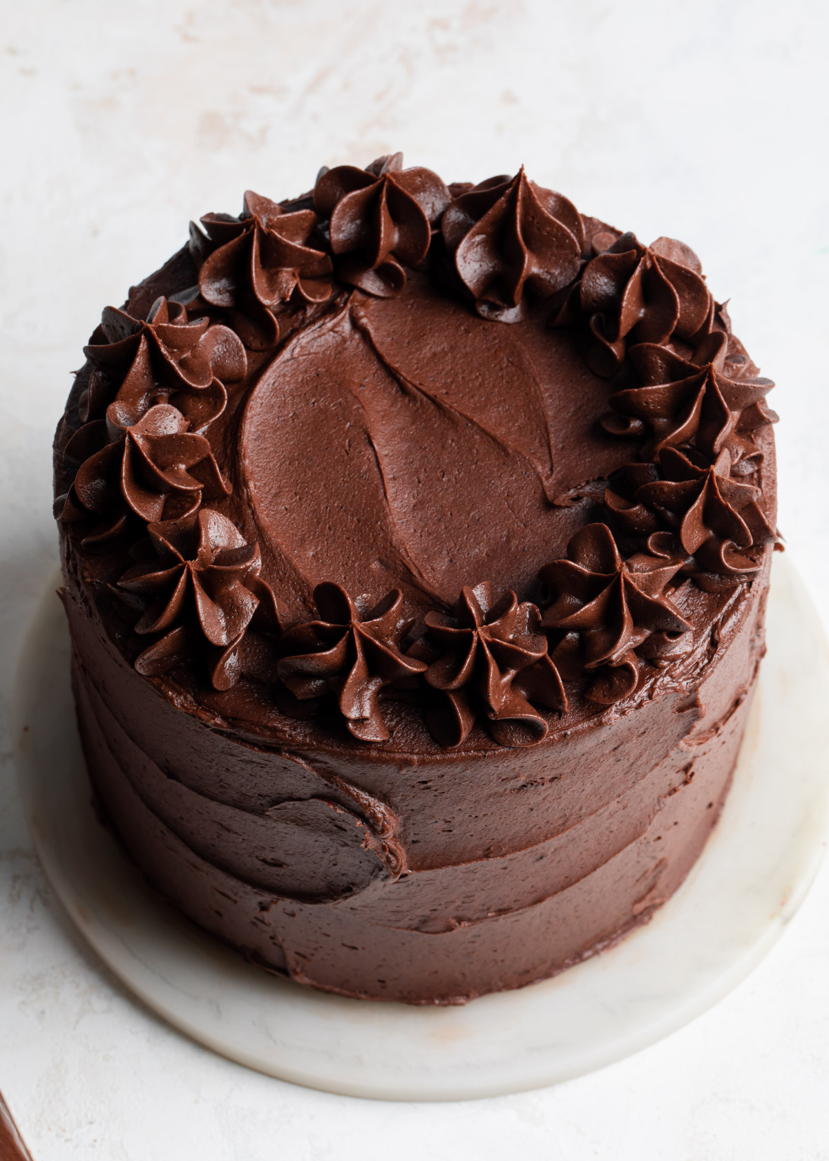 Fudge frosting piped around the top of a cake
