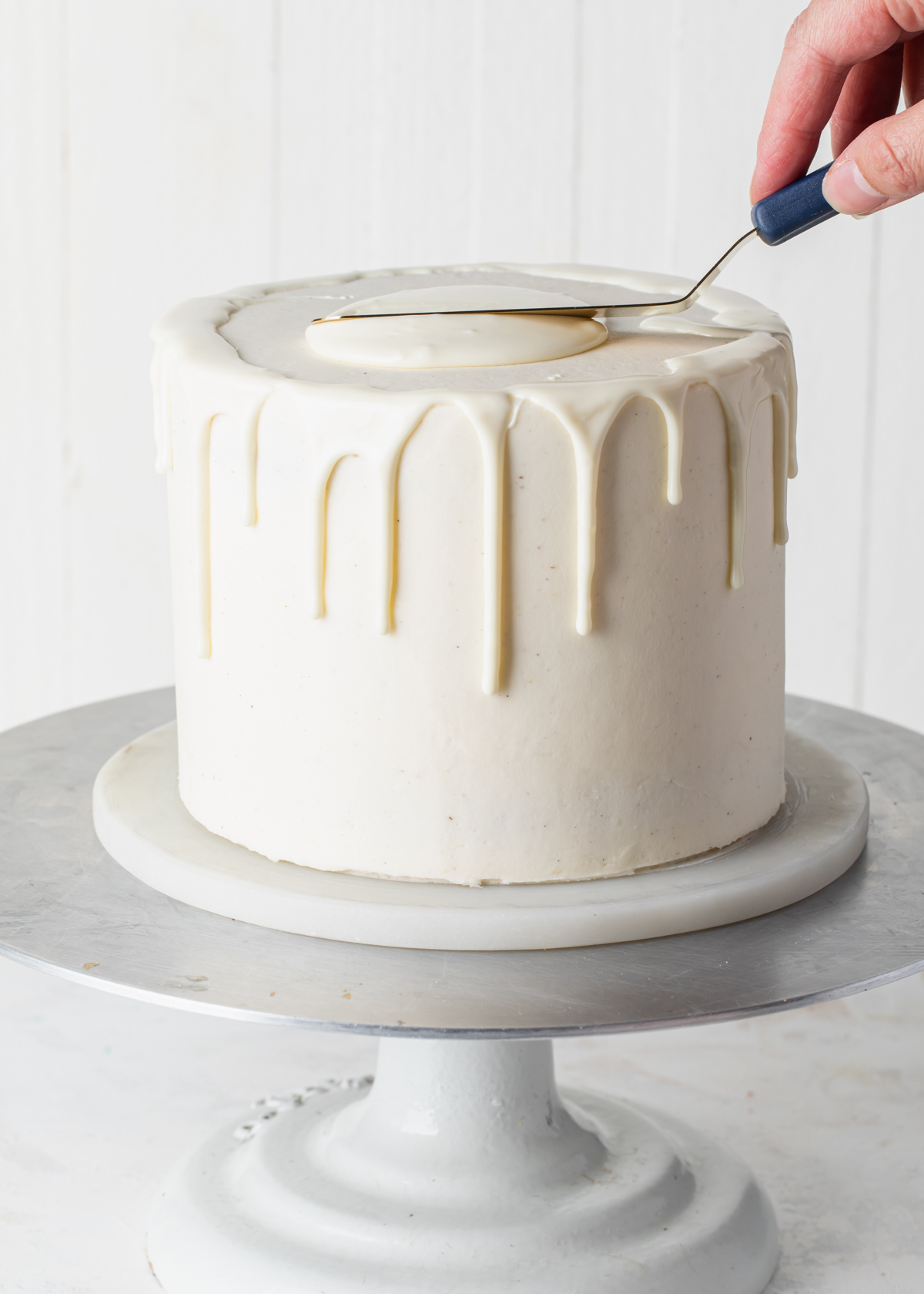 Spread white chocolate ganache on the top of a drip cake