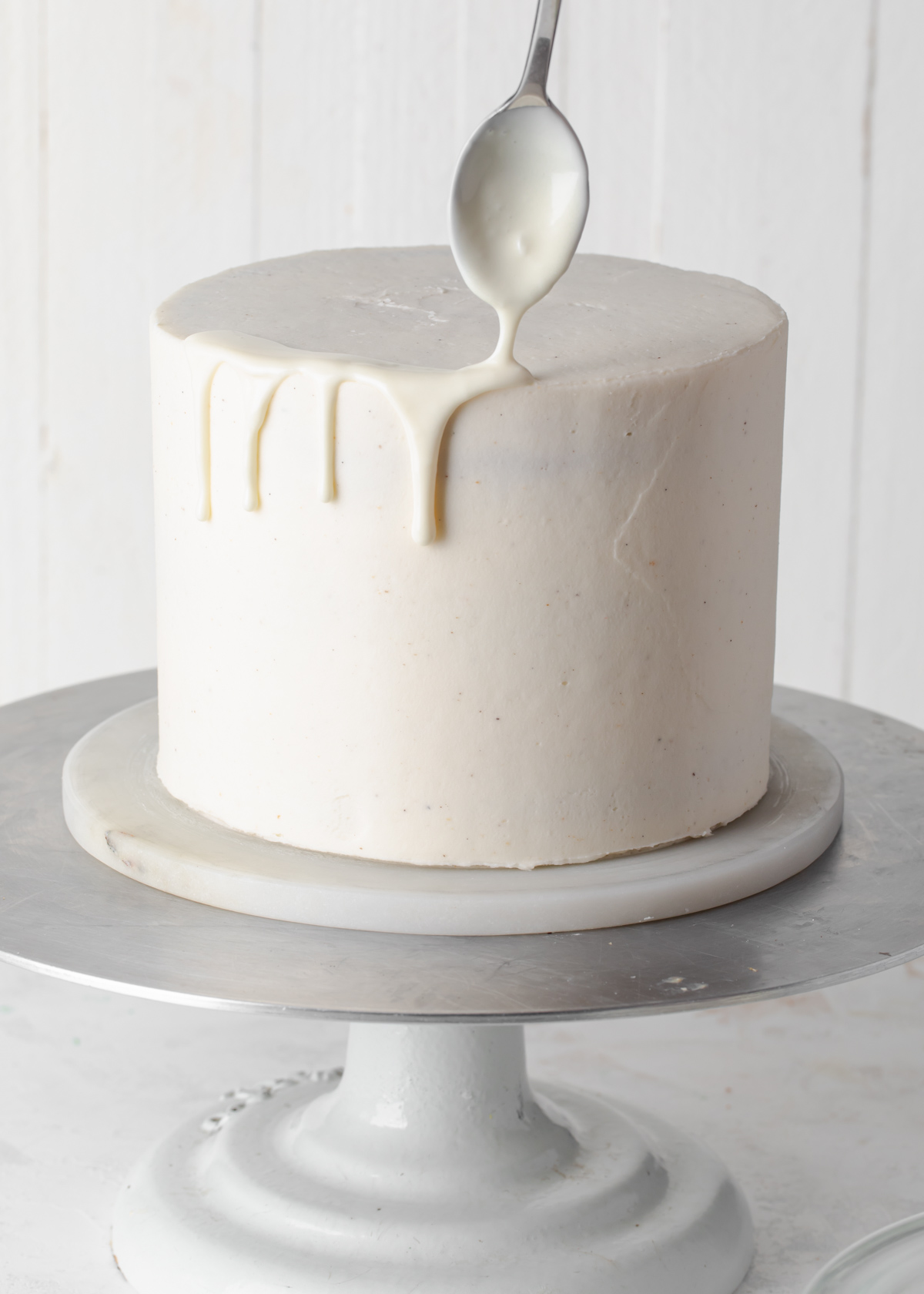 Adding a white chocolate drip to a frosted cake