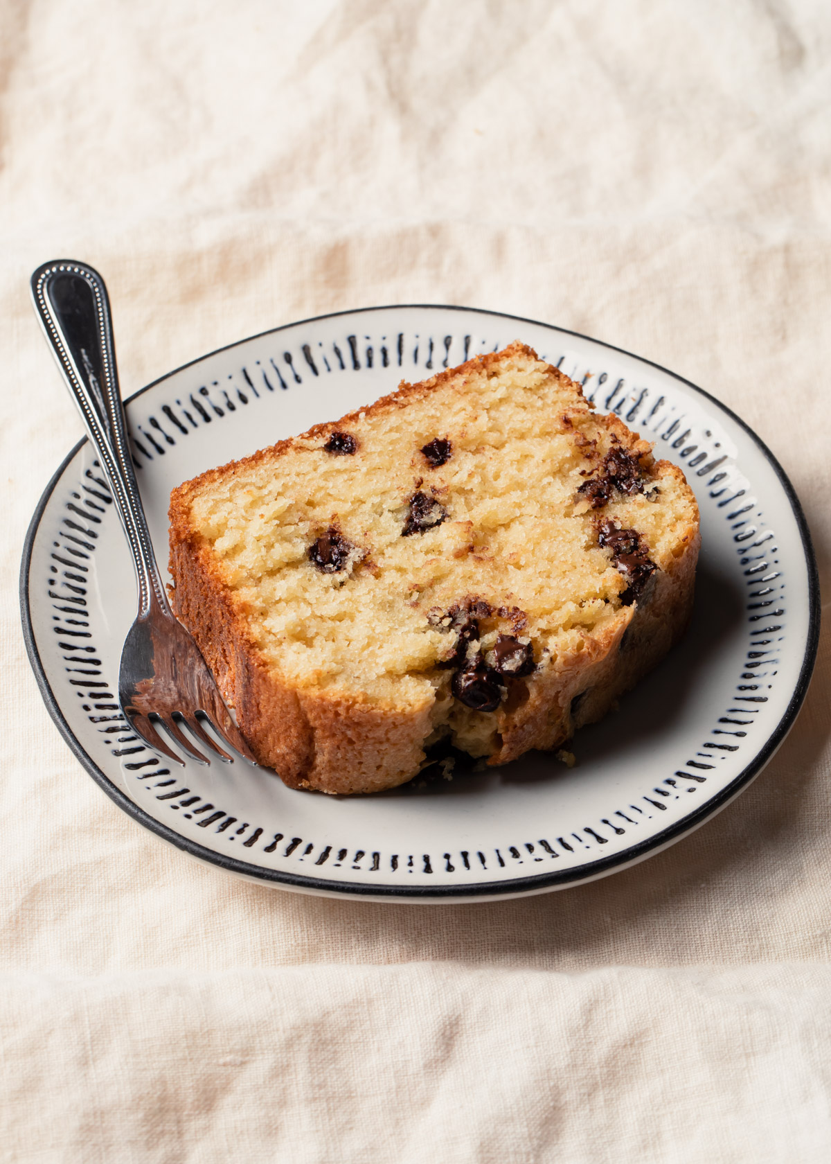 A slice of chocolate chip pound cake on a plate with a fork