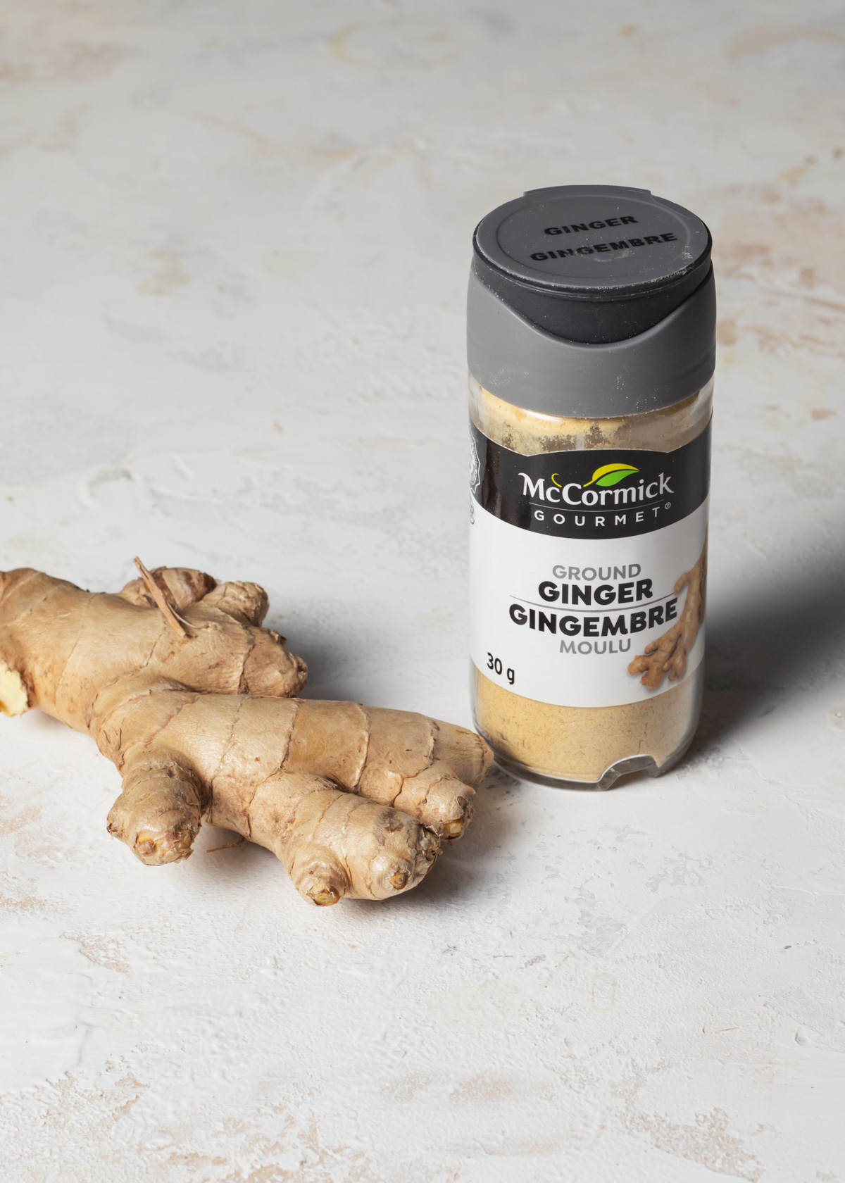 Fresh ginger root next to a jar of ground ginger