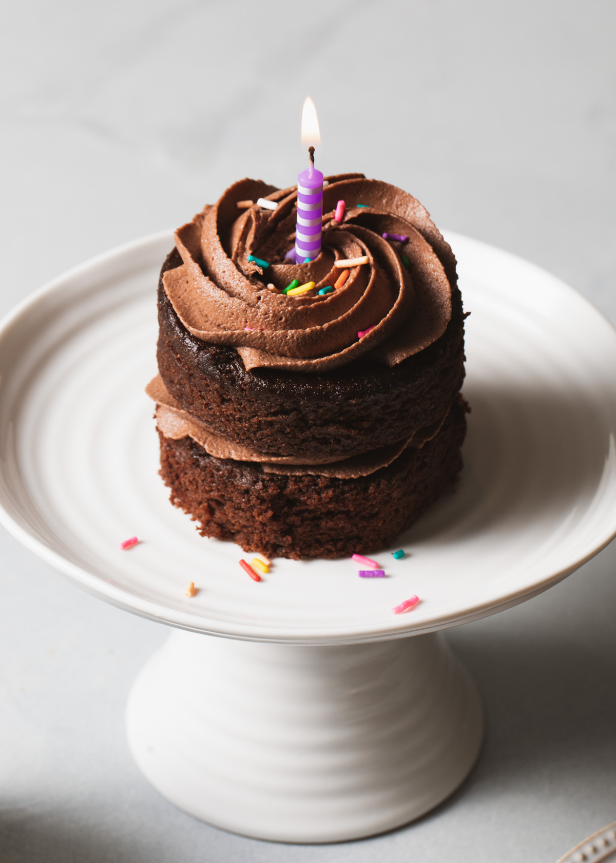A mini chocolate cake on a small white cake stand