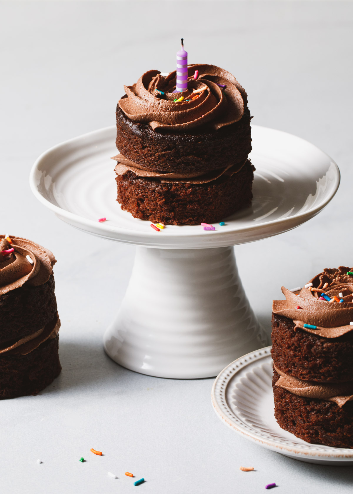Three mini chocolate cakes on a white cake stand