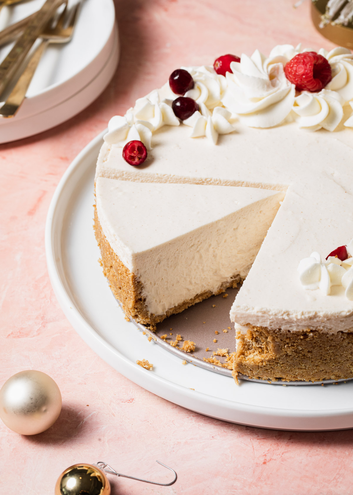 A sliced eggnog cheesecake on a platter set on a pink tabletop