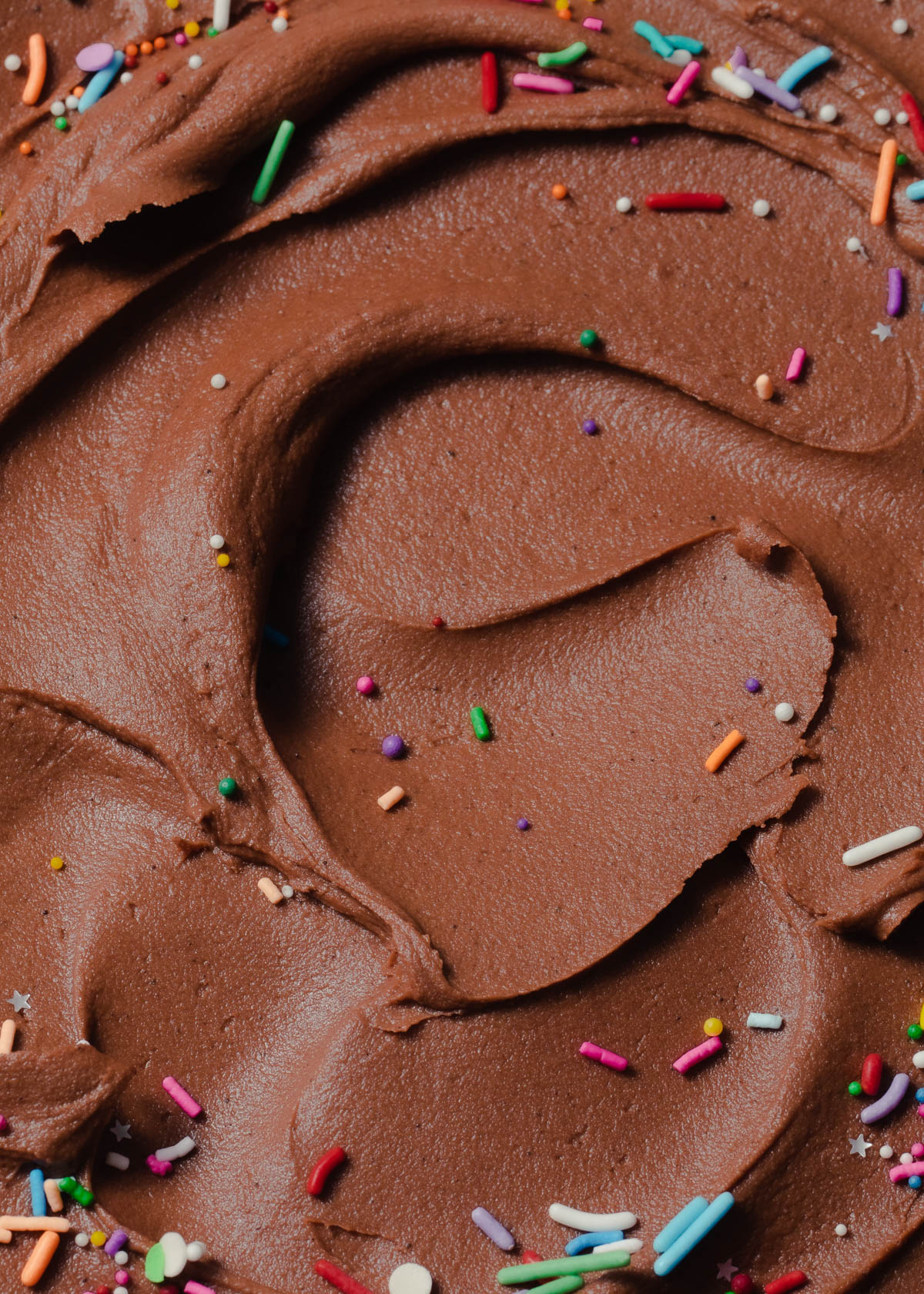 A close up Nutella buttercream swirled in a bowl with sprinkles