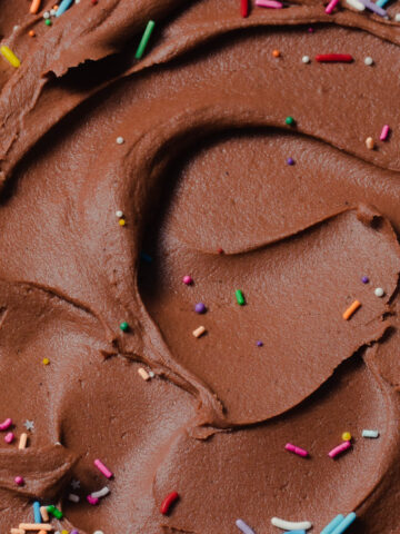A close up Nutella buttercream swirled in a bowl with sprinkles