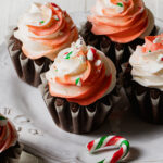 Peppermint buttercream swirled on top of chocolate cupcakes with candy canes bits on top