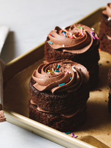 Mini chocolate cakes with swirls of chocolate frosting and sprinkles