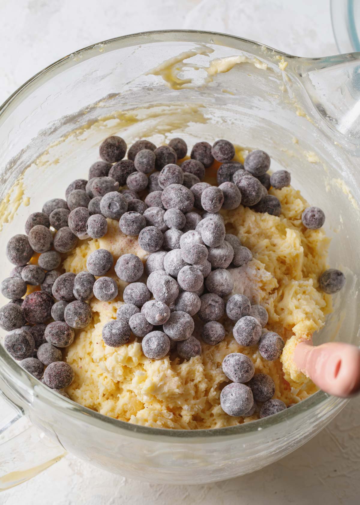 Blueberries tossed in flour being added to cake batter
