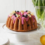 A lemon blueberry bundt cake with blueberry icing and decorated with lemon slice